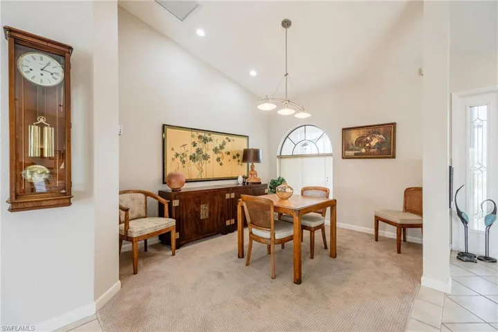 Dining space with light carpet and high vaulted ceiling