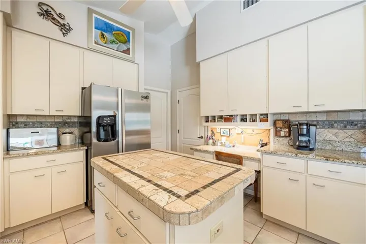 Kitchen featuring ceiling fan, white cabinets, light tile patterned floors, tasteful backsplash, and a center island