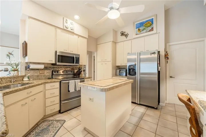 Kitchen featuring a center island, lofted ceiling, backsplash, appliances with stainless steel finishes, and ceiling fan