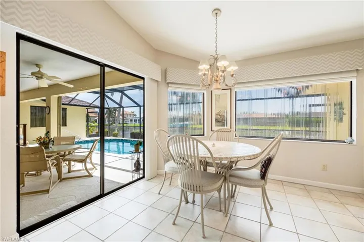 Tiled dining area featuring ceiling fan with notable chandelier