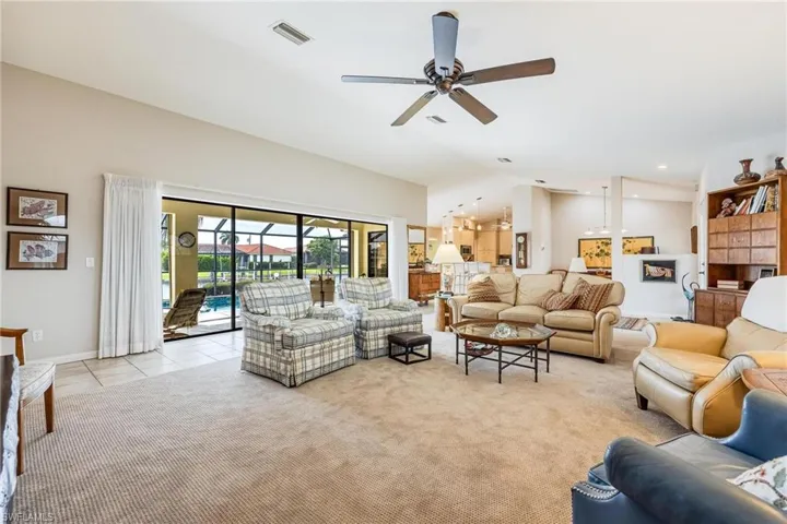 Living room featuring lofted ceiling, ceiling fan, and light tile patterned floors