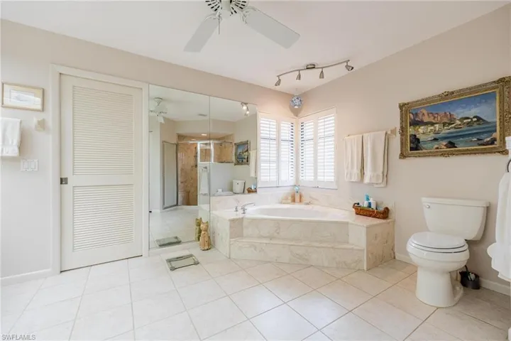 Bathroom featuring independent shower and bath, toilet, ceiling fan, and tile patterned floors