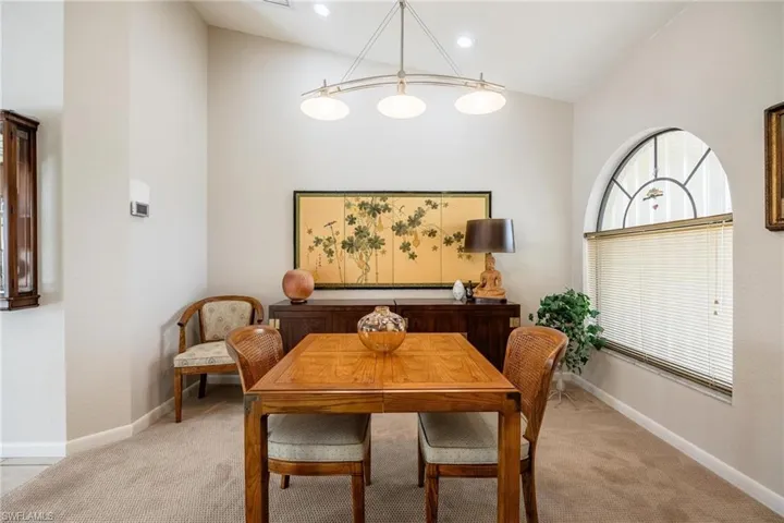 Dining area with light carpet and lofted ceiling