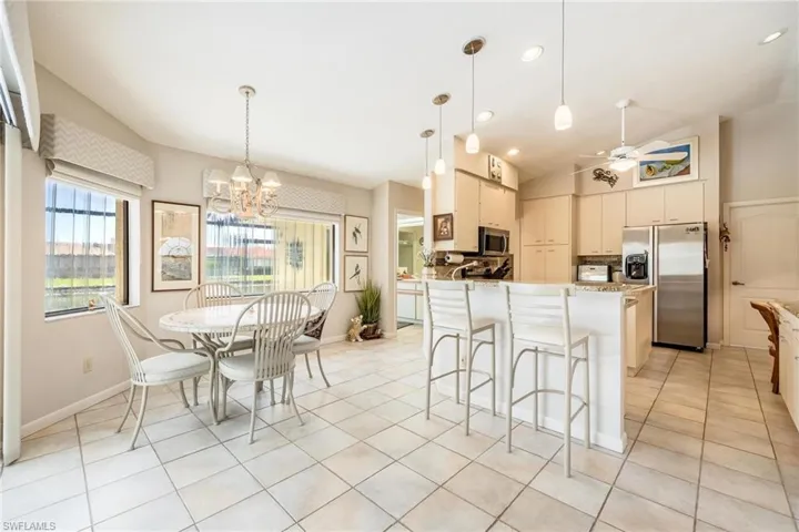 Kitchen with light tile patterned flooring, vaulted ceiling, ceiling fan with notable chandelier, pendant lighting, and stainless steel appliances
