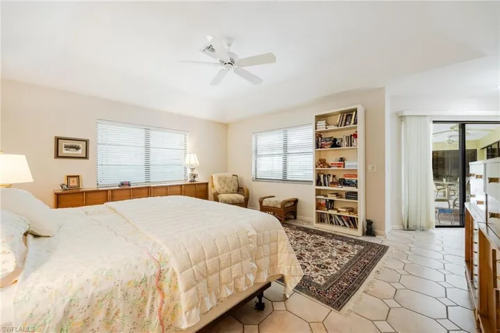 Tiled bedroom featuring multiple windows, access to outside, and ceiling fan