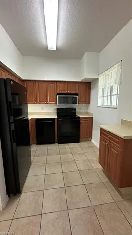 Kitchen featuring black appliances, a textured ceiling, and light countertops