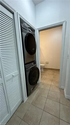 Laundry area featuring stacked washer and dryer, laundry area, and light tile patterned floors