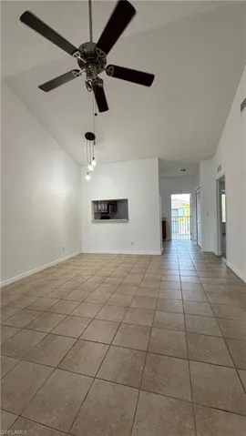 Unfurnished living room featuring tile patterned floors, a ceiling fan, baseboards, and high vaulted ceiling