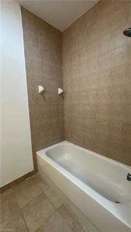 Bathroom featuring shower / bathing tub combination, a textured ceiling, and baseboards