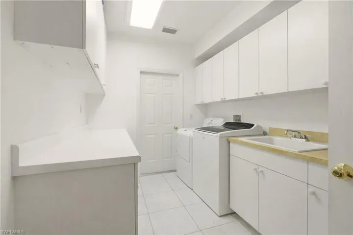 Laundry area featuring cabinet space, light tile patterned floors, and washing machine and dryer