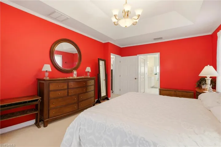 Bedroom with hanging lights, crown molding, and light colored carpet