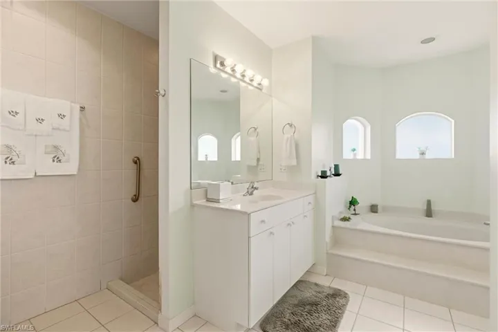 Full bathroom with vanity, light tile patterned floors, a bath, and a walk in shower