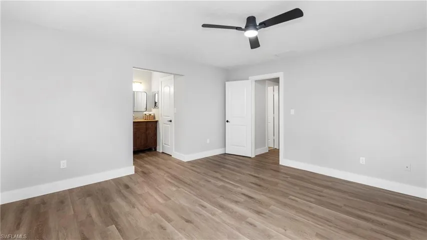 Unfurnished bedroom featuring ceiling fan, connected bathroom, and wood finished floors