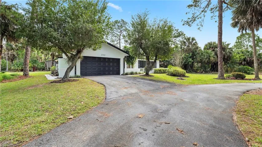 View of front facade with a front lawn, asphalt driveway, stucco siding, and a garage