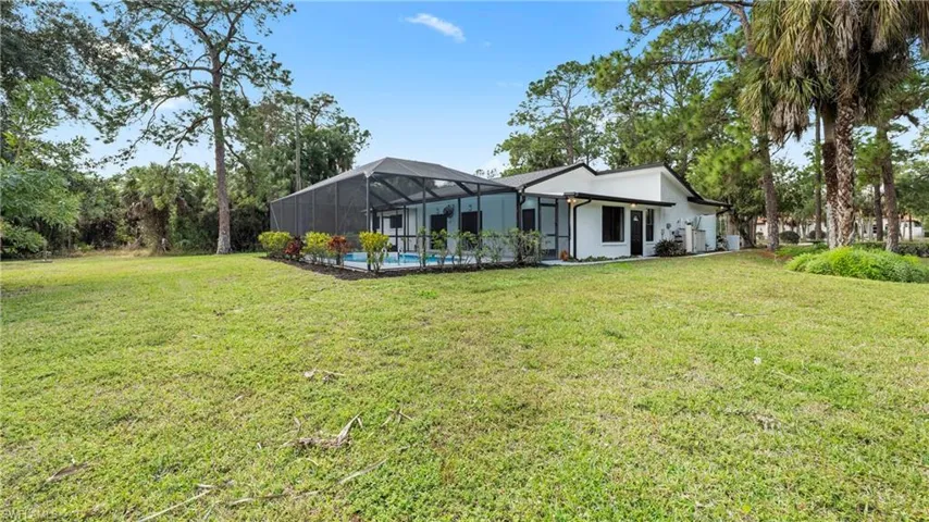 Rear view of house with a lanai, a yard, a sunroom, and an outdoor pool