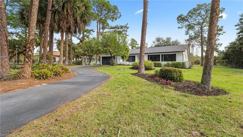 Ranch-style house featuring asphalt driveway and a front lawn