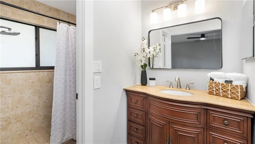 Full bathroom with a stall shower, vanity, and ceiling fan
