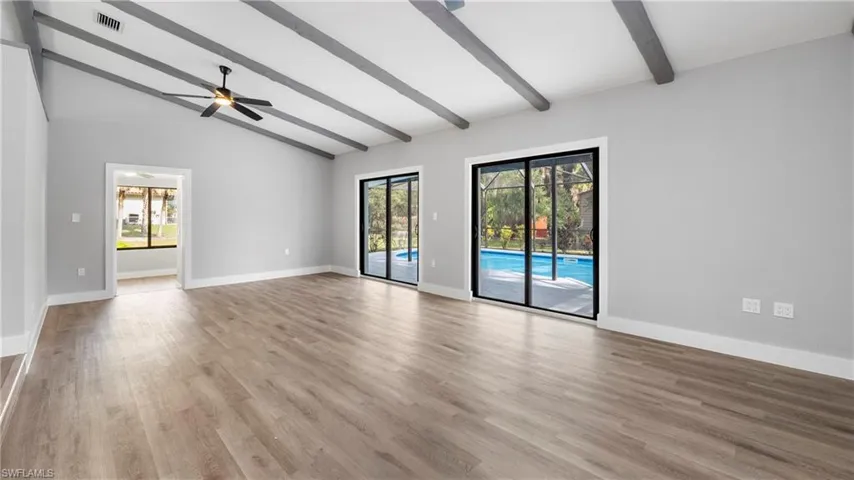 Spare room with beamed ceiling, high vaulted ceiling, light wood-style flooring, and ceiling fan