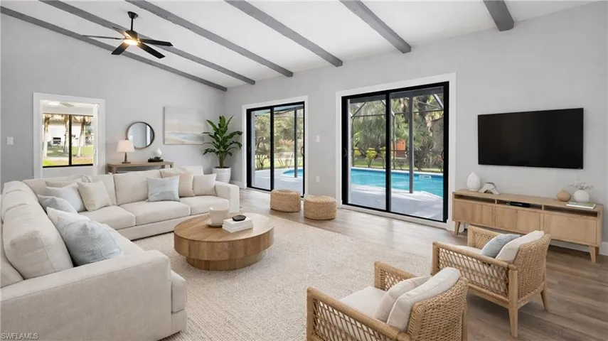 Virtually Staged Living area with wood finished floors, healthy amount of natural light, lofted ceiling, a ceiling fan, and a sunroom
