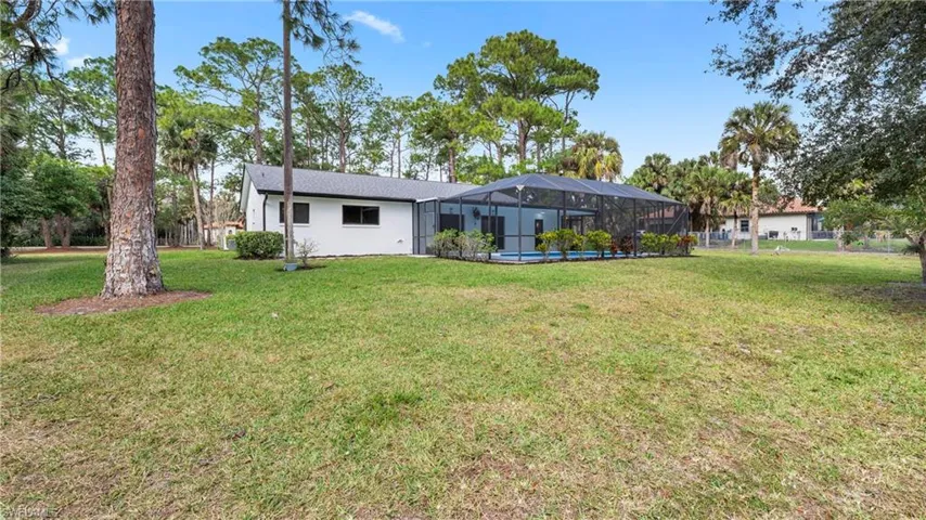 Rear view of house with glass enclosure, a lawn, and a sunroom