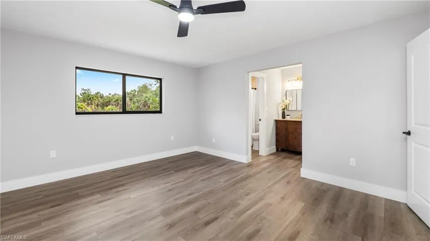 Unfurnished bedroom featuring wood finished floors, a ceiling fan, and ensuite bathroom