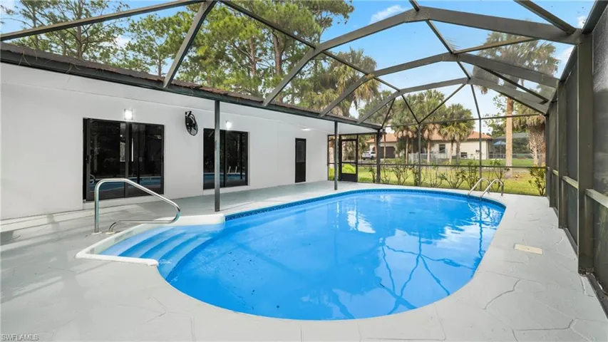 Outdoor pool with glass enclosure, a patio area, and a sunroom