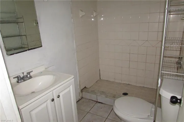 Bathroom with vanity, a tile shower, toilet, and tile patterned flooring