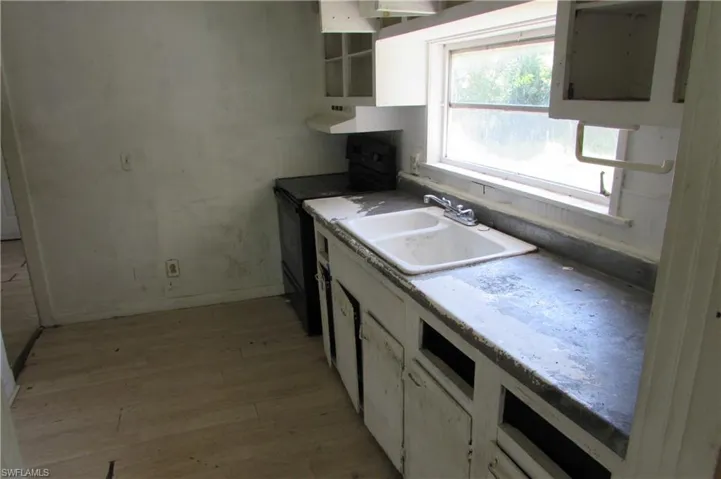 Kitchen with sink, white cabinetry, range with electric stovetop, and light hardwood / wood-style floors