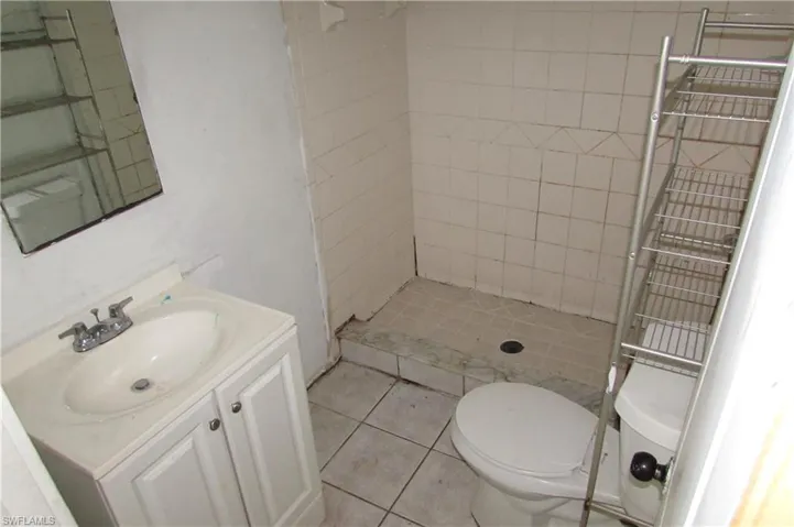 Bathroom featuring tile patterned floors, vanity, toilet, and tiled shower