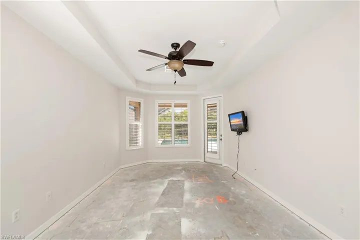 Empty room featuring a raised ceiling and a ceiling fan