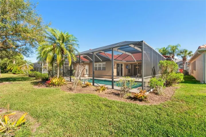 Back of house featuring a sunroom, a lawn, glass enclosure, a patio area, and an outdoor pool