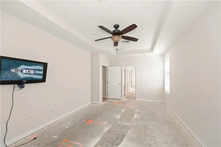 Unfurnished bedroom featuring a raised ceiling and ceiling fan