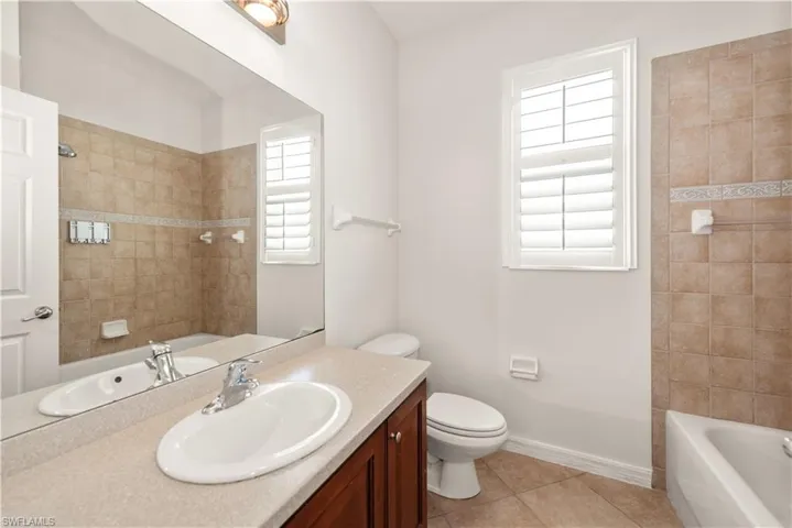 Bathroom with vanity, bathtub / shower combination, and light tile patterned floors