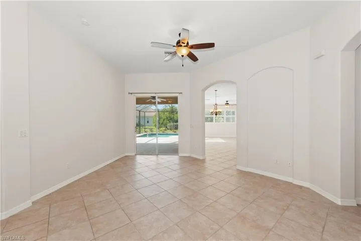 Spare room with arched walkways, a ceiling fan, a chandelier, a sunroom, and light tile patterned floors