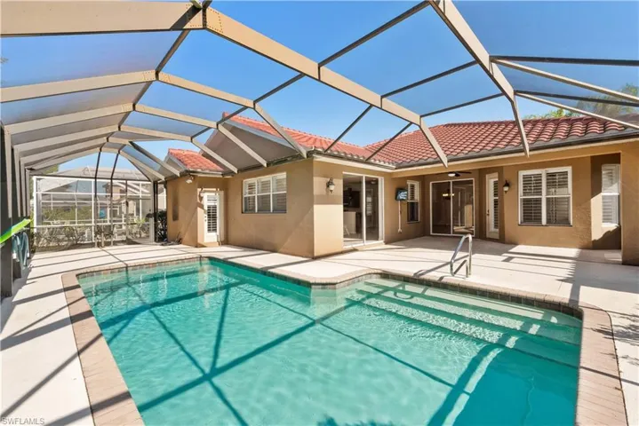 Outdoor pool with a sunroom, glass enclosure, and a patio area