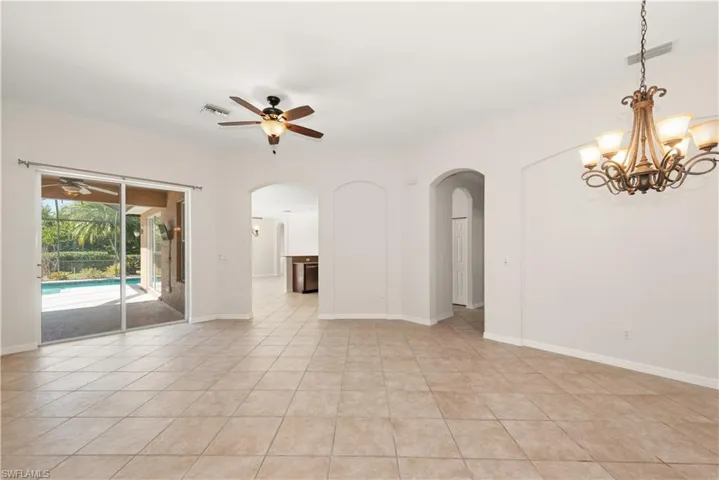 Spare room featuring a ceiling fan, light tile patterned flooring, and a chandelier