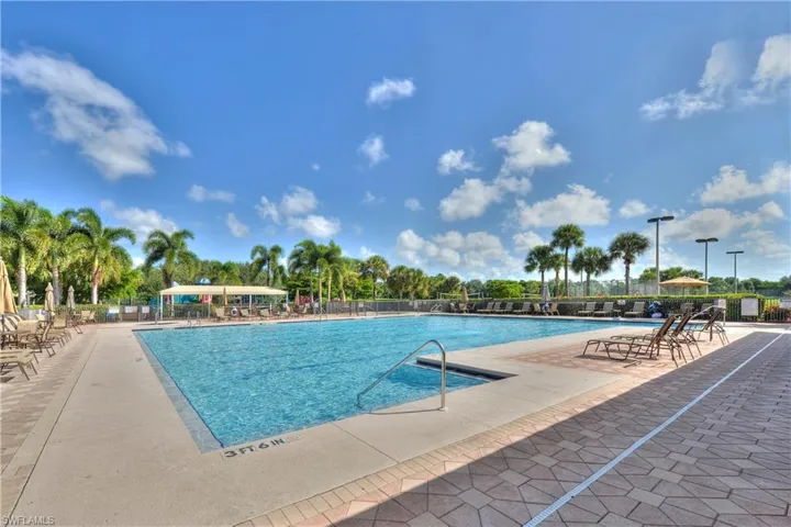 Community pool with a patio area and view of scattered trees