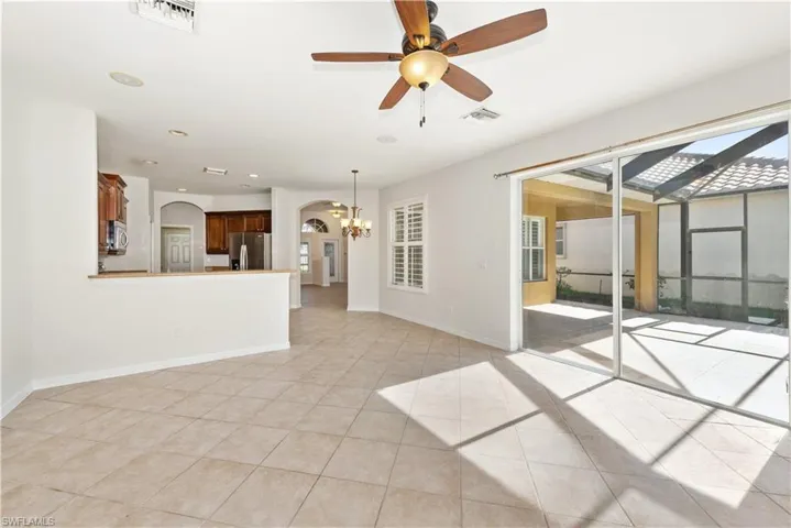 Unfurnished living room featuring ceiling fan, a sunroom, recessed lighting, arched walkways, and a chandelier