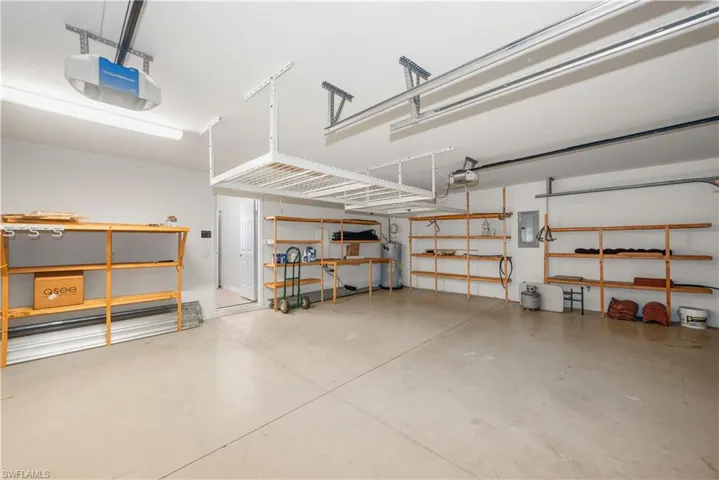 Garage with a garage door opener, electric panel, and water heater