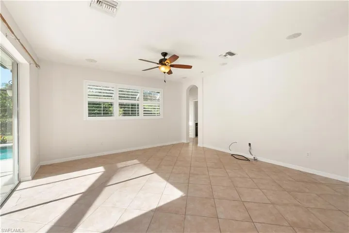 Unfurnished room featuring arched walkways, ceiling fan, and light tile patterned flooring