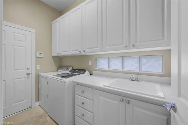Laundry room with sink, separate washer and dryer, and cabinets