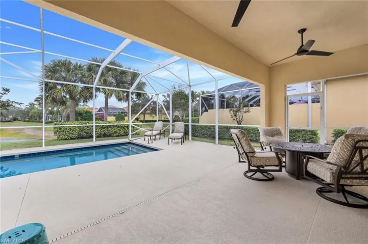 View of swimming pool featuring ceiling fan, a patio area, and glass enclosure