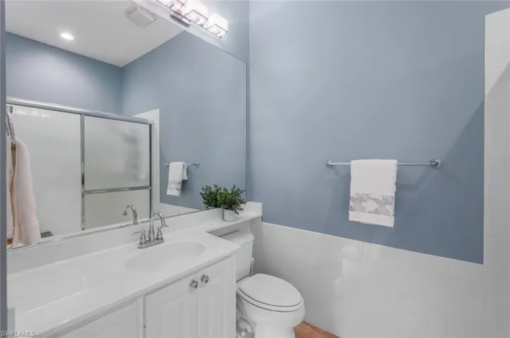 Bathroom with tile walls, toilet, walk in shower, and vanity