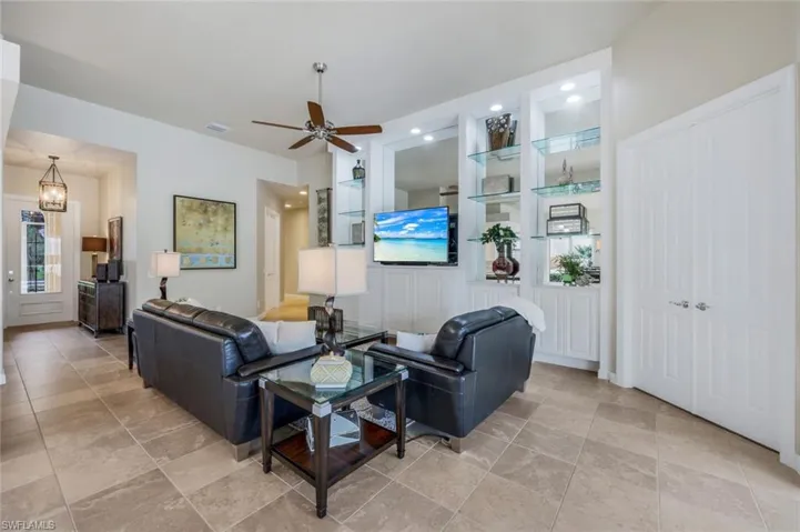 Living room with ceiling fan and built in shelves