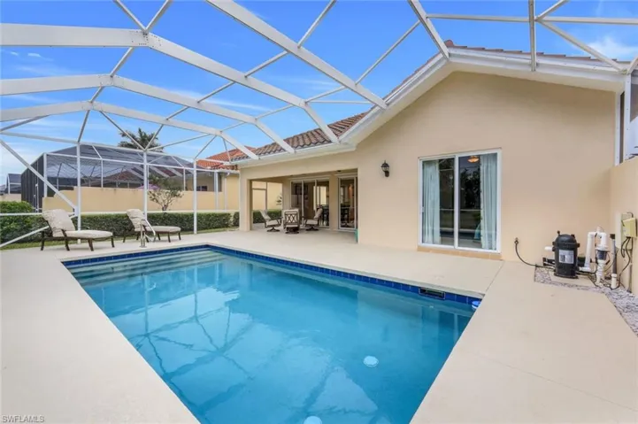 View of pool with glass enclosure and a patio