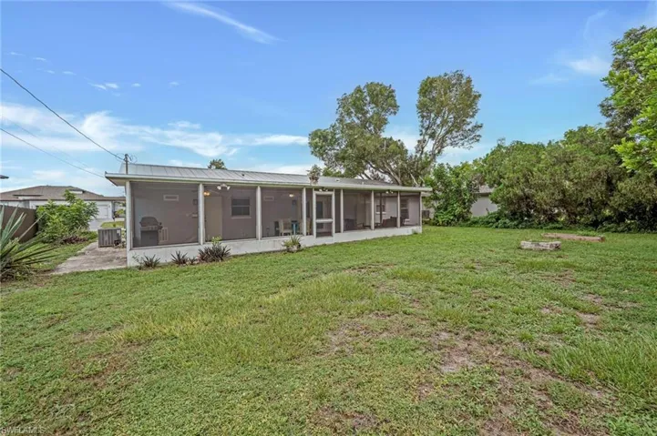 Rear view of property with a lawn and a sunroom