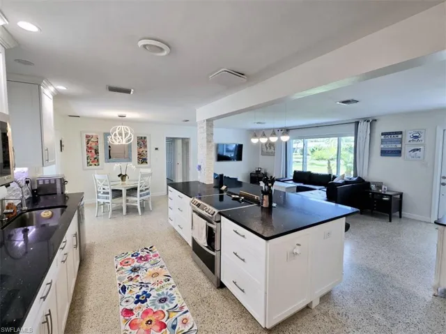 Kitchen with hanging light fixtures, a center island, white cabinets, sink, and appliances with stainless steel finishes