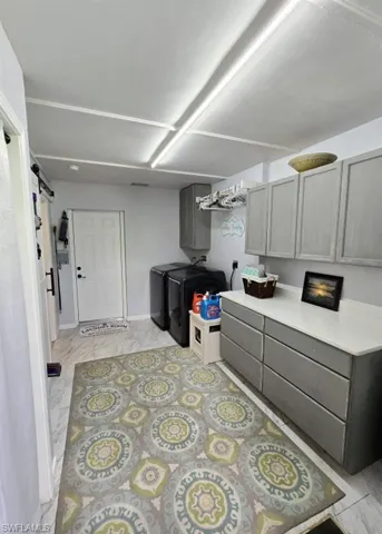 Kitchen with a barn door, gray cabinets, washing machine and clothes dryer, and light tile floors
