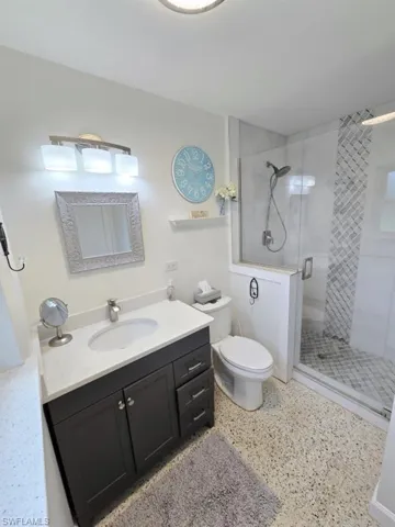 Bathroom with an enclosed shower, vanity, and toilet