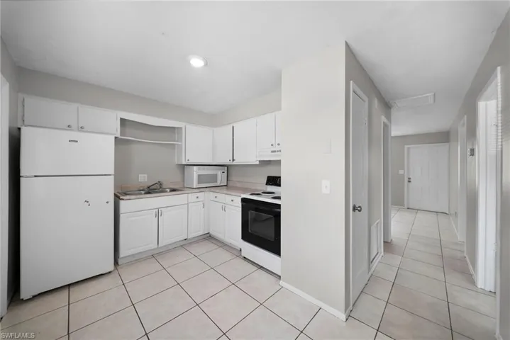 Kitchen featuring white appliances, white cabinets, light countertops, open shelves, and light tile patterned floors